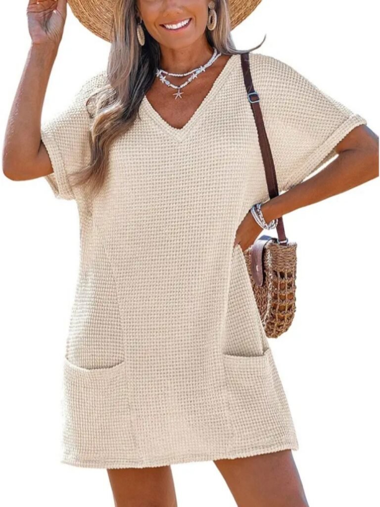 Beige waffle-knit V-neck tunic dress with short sleeves and front pockets, worn by a woman with straw hat and woven bag.