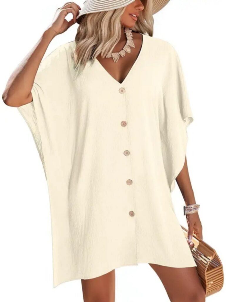 Beige V-neck button-front tunic dress with short flutter sleeves, textured fabric, model holding woven basket and wearing straw hat.