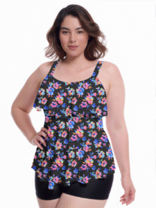 Plus-size woman modeling black floral ruffle tank top swimwear with colorful flowers, paired with black shorts for swimwear showcase.