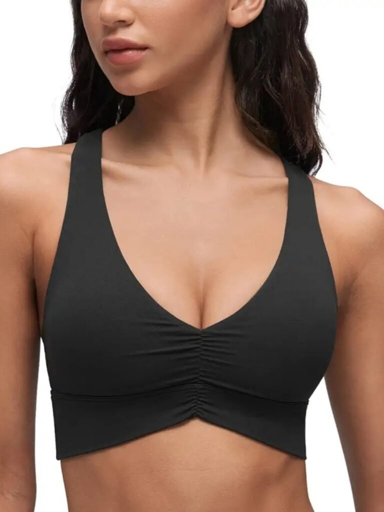 Black ruched sports bra with V-neck and wide straps, made from stretchy performance fabric for activewear.