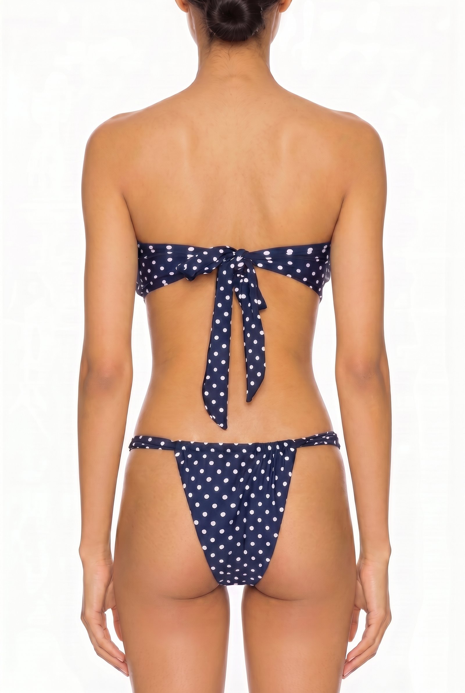 Back view of a navy blue and white polka dot strapless tie-back bikini set with cheeky coverage bottoms.