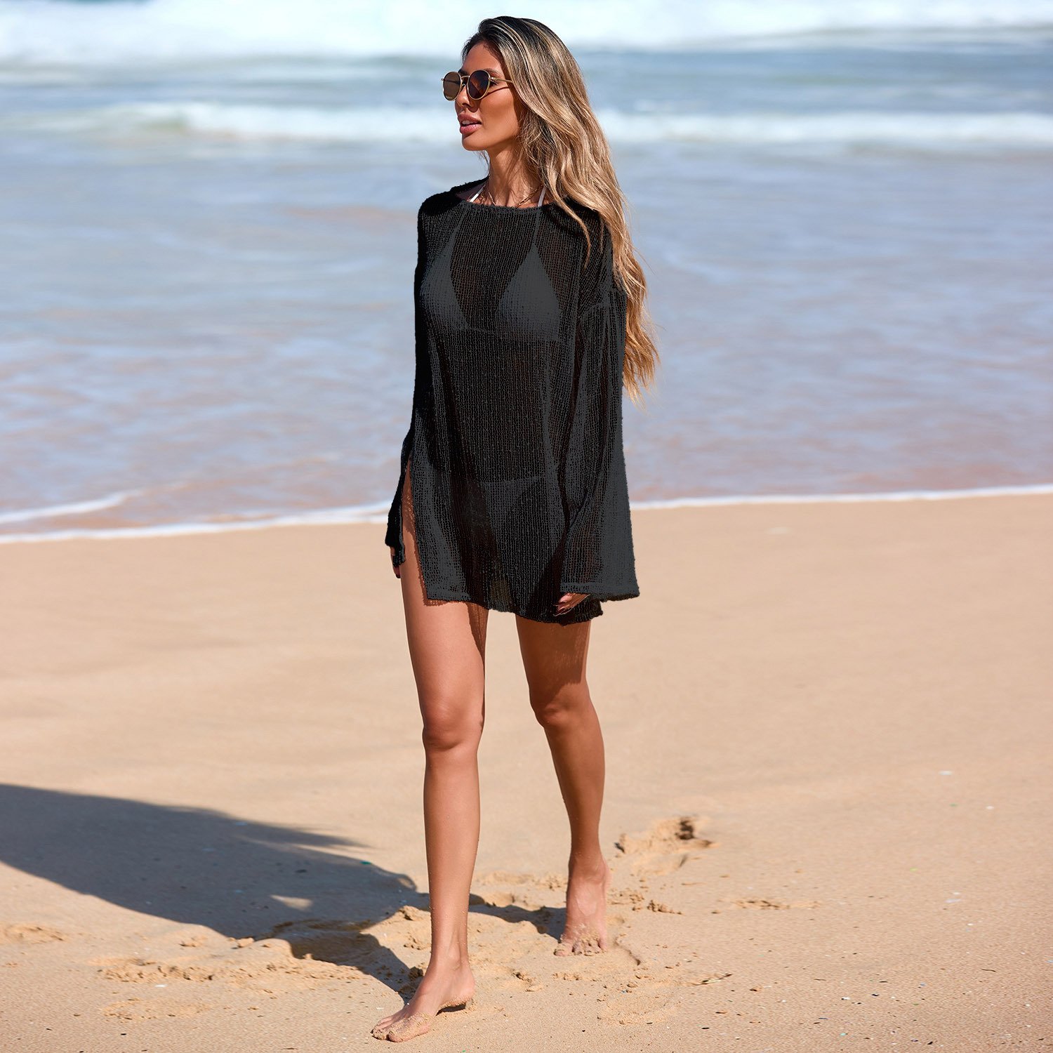 A woman models a black long sleeve open weave cover-up tunic with bell sleeves and high side slits