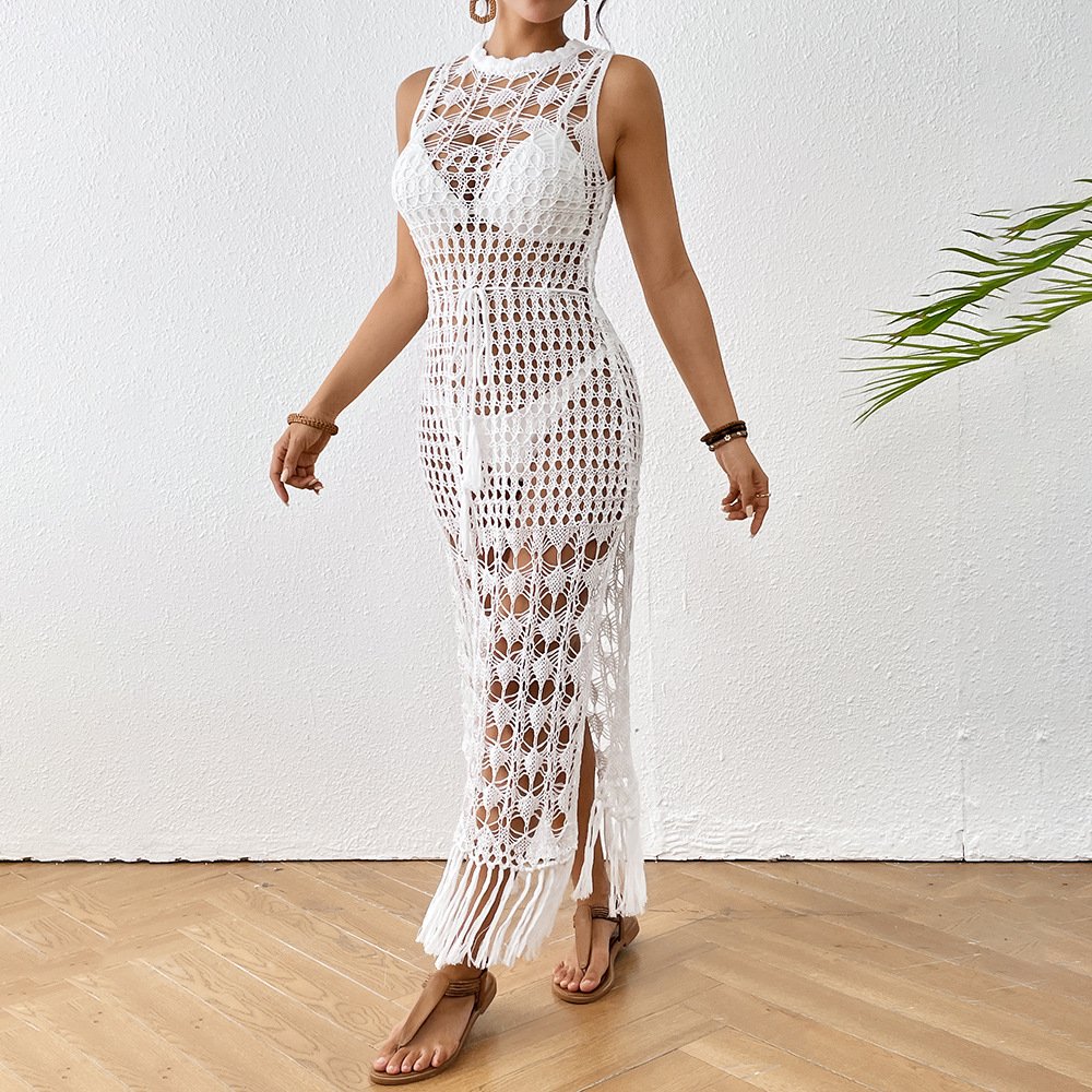 White sleeveless crochet maxi cover-up dress with high neckline, open back, drawstring waist, side slits, and fringed hem.