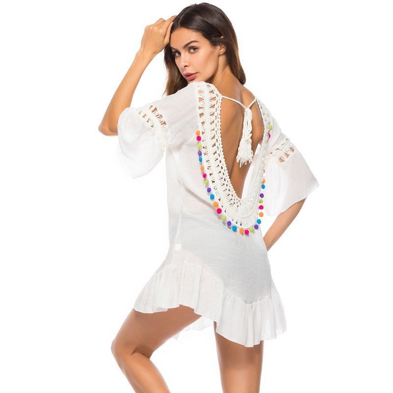 White mini cover-up tunic with bell sleeves, deep back cutout, crochet trim, and colorful pom-poms.