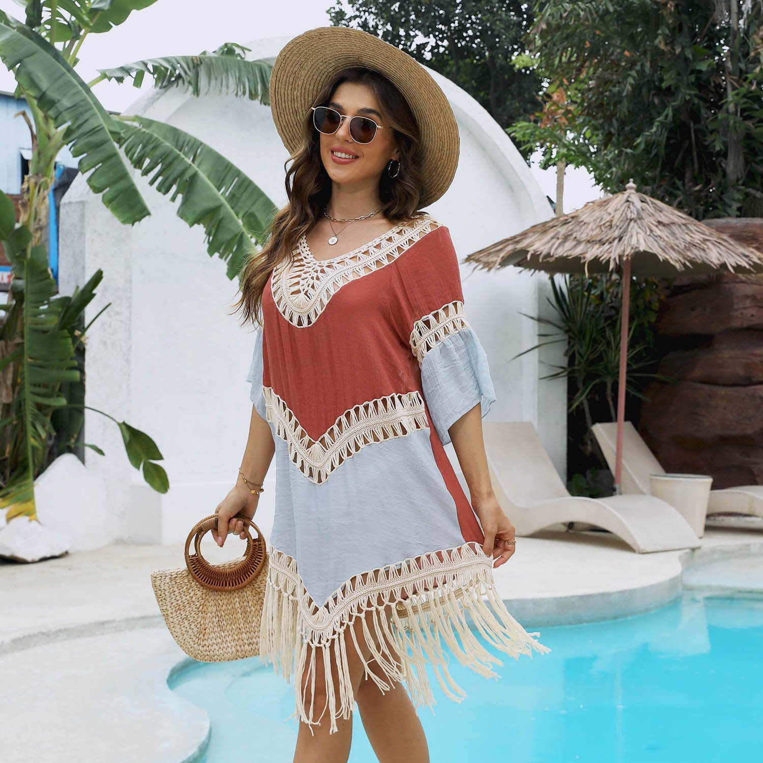 Woman wearing a rust and light blue color-block beach cover-up featuring a deep V-neck, crochet trim, and fringe