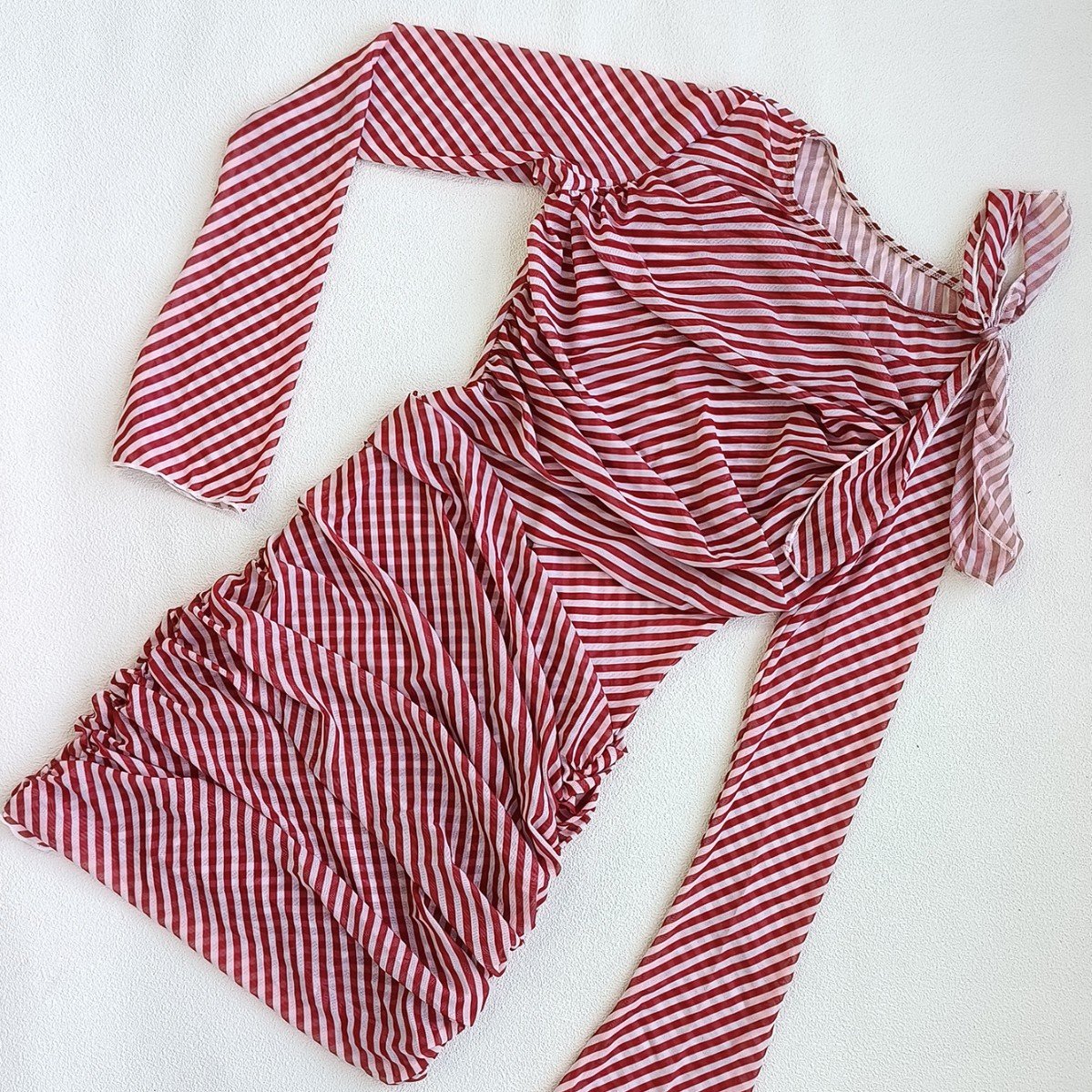 Red and white striped long sleeve mini cover-up dress featuring diagonal ruching and an asymmetrical shoulder tie.