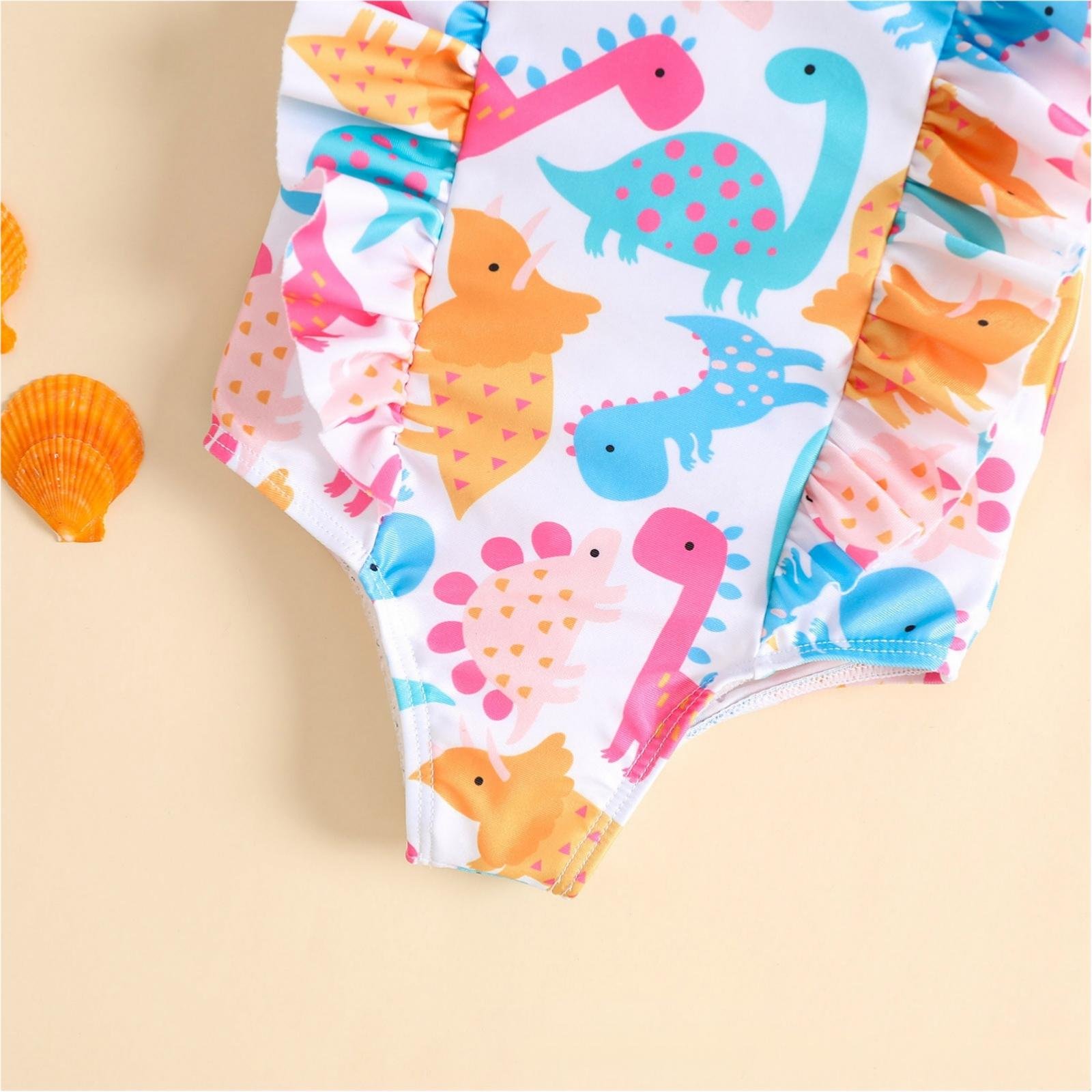 Girls' one-piece swimsuit featuring a colorful dinosaur print with ruffled side panels and high-cut legs.