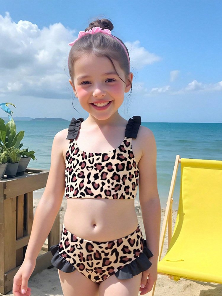 Young girl wearing a leopard print two-piece bikini with ruffled black straps and high-waisted bottoms featuring ruffled trim.