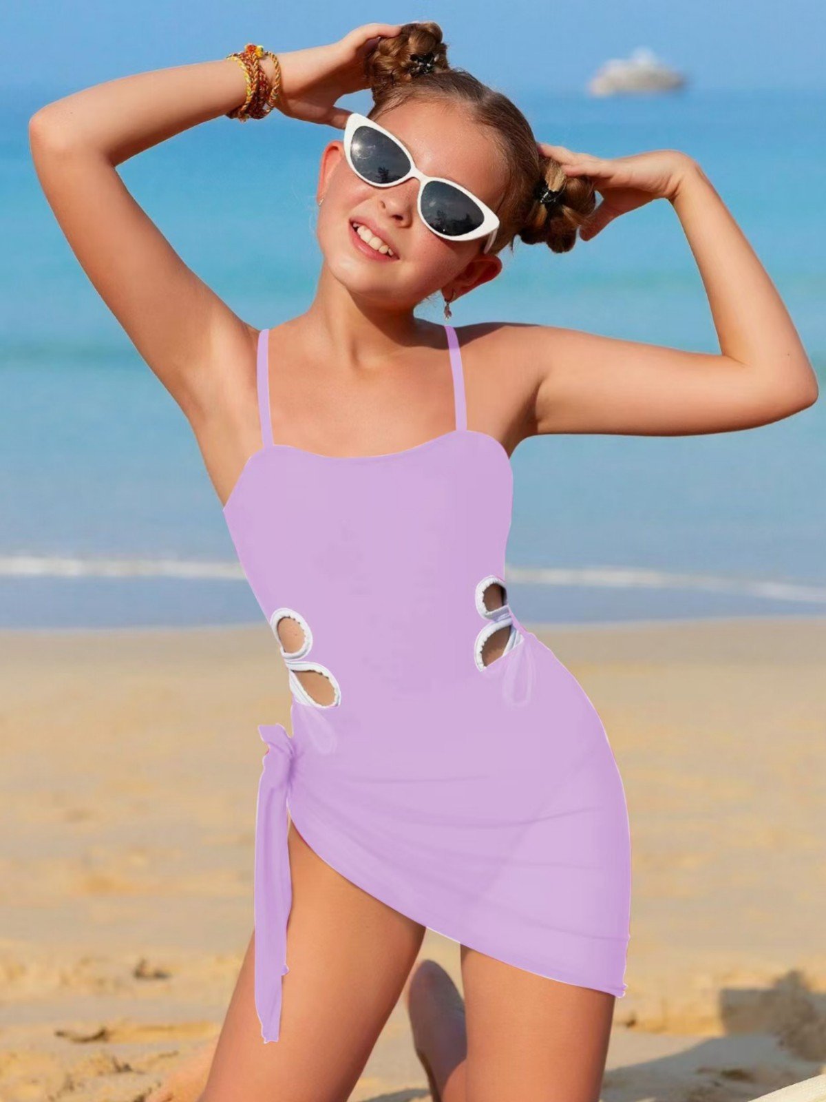Girl wearing a lavender one-piece swimsuit with side cutouts and a matching tie-side sarong skirt.