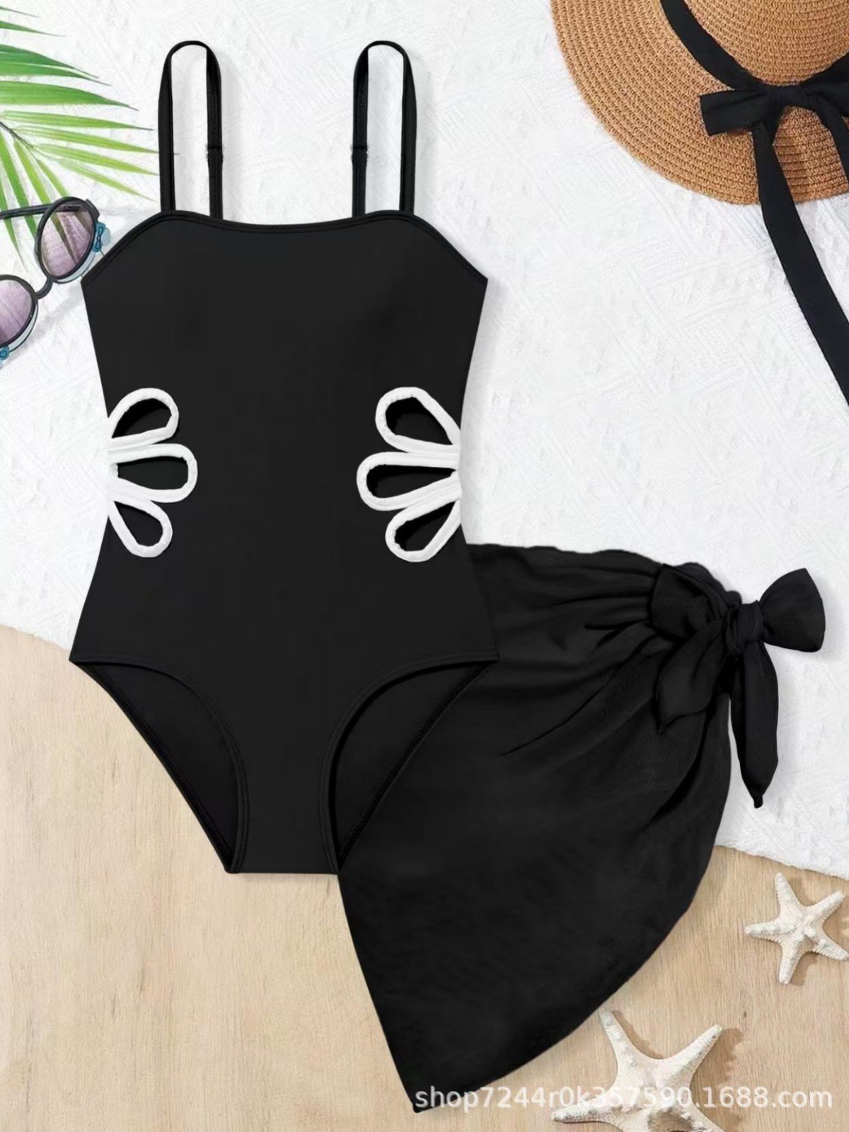 Black girls' one-piece swimsuit with thin straps, white-trimmed side cutouts, and a matching tie-side sarong skirt.
