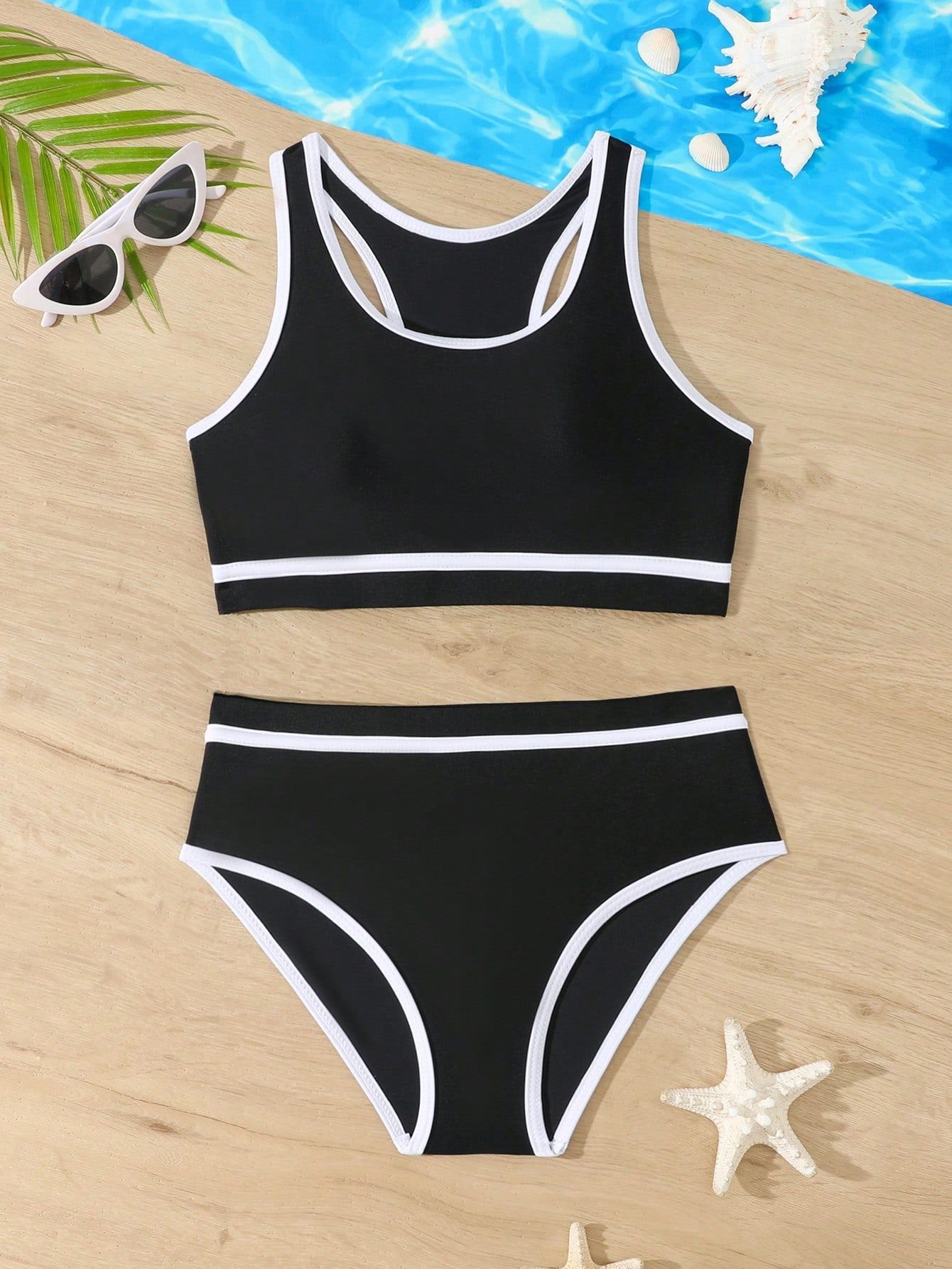 Black girls' two-piece swimsuit with white contrast trim, featuring a racerback crop top and high-waist bottoms.