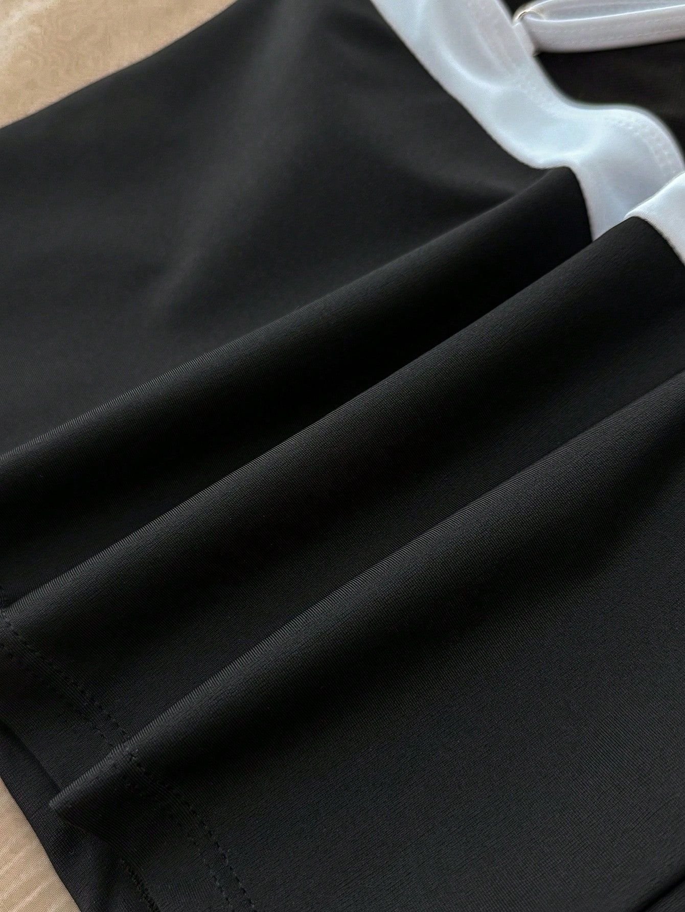 Close-up of black swimwear fabric with white contrasting trim and visible stitching details.