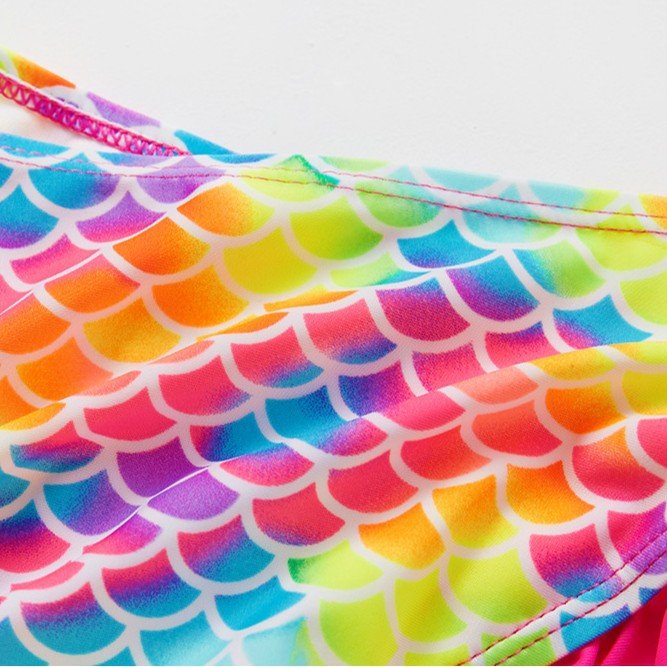 Close-up of a colorful rainbow mermaid scale print fabric detail on a girls' swimwear top.