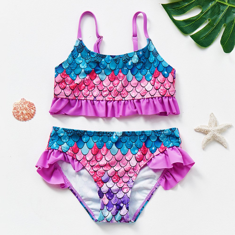 Girls' mermaid scale print tankini set with adjustable purple straps, ruffled hem top, and ruffled side bikini bottoms.