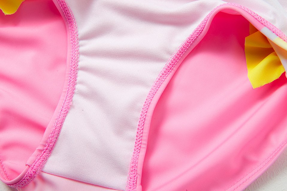 Close-up of a pink and light pink girls' swimsuit bottom featuring pink trim and yellow ruffle details.