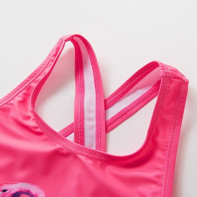 Close-up of a pink girls' one-piece swimsuit featuring a scoop neckline and criss-cross racerback straps with white lining.