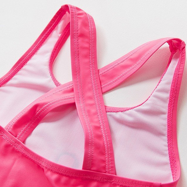 Close-up of a pink girls' one-piece swimsuit featuring a criss-cross racerback design with wide straps and light pink