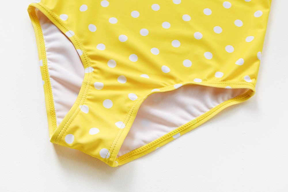 Yellow one-piece swimsuit bottom featuring white polka dots and white lining.