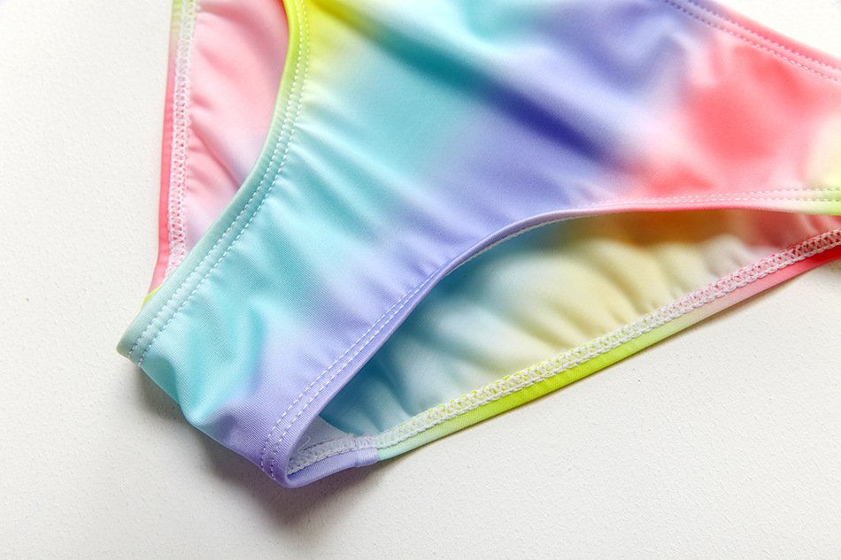 Close-up detail of a pastel rainbow tie-dye bikini bottom with white stitching.