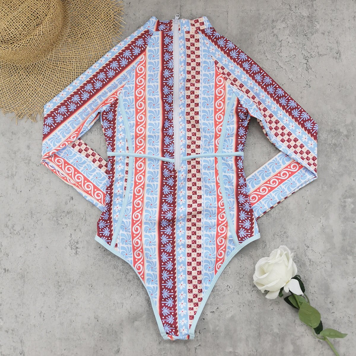 Patterned long sleeve zip-up one-piece swimsuit with high neck and waist tie.