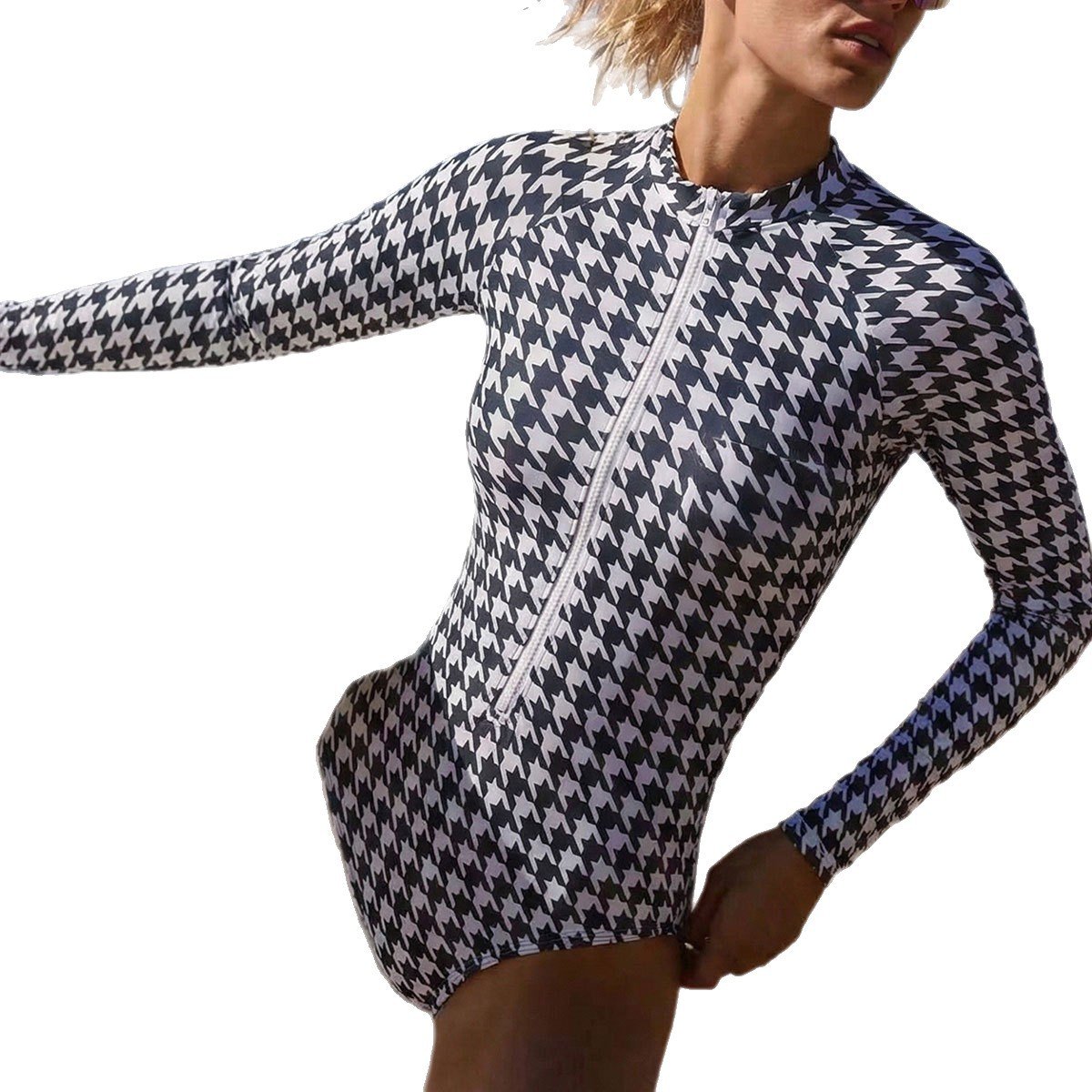 A woman wearing a black and white houndstooth print long sleeve one-piece surf suit with a front zip