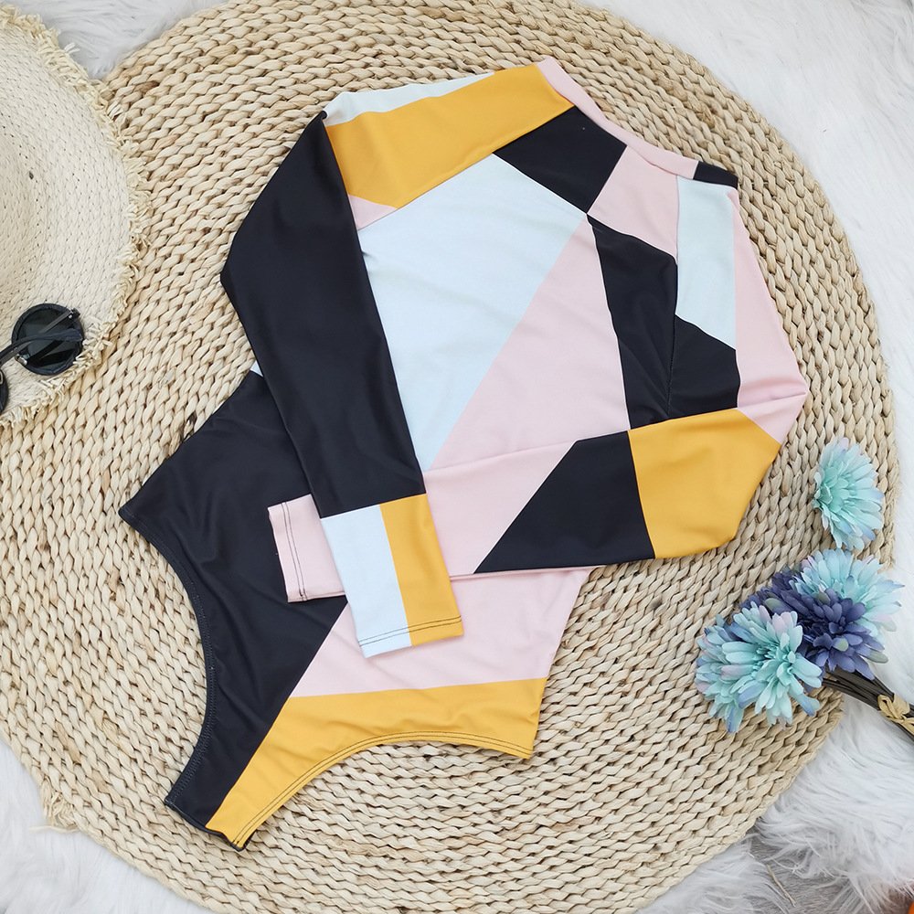 Long sleeve geometric color-block rash guard one-piece swimsuit with crew neck and zip front.