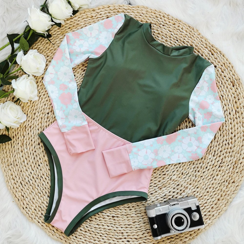 Flat lay of a long sleeve colorblock one piece swimsuit featuring a green bodice, pink lower section, and