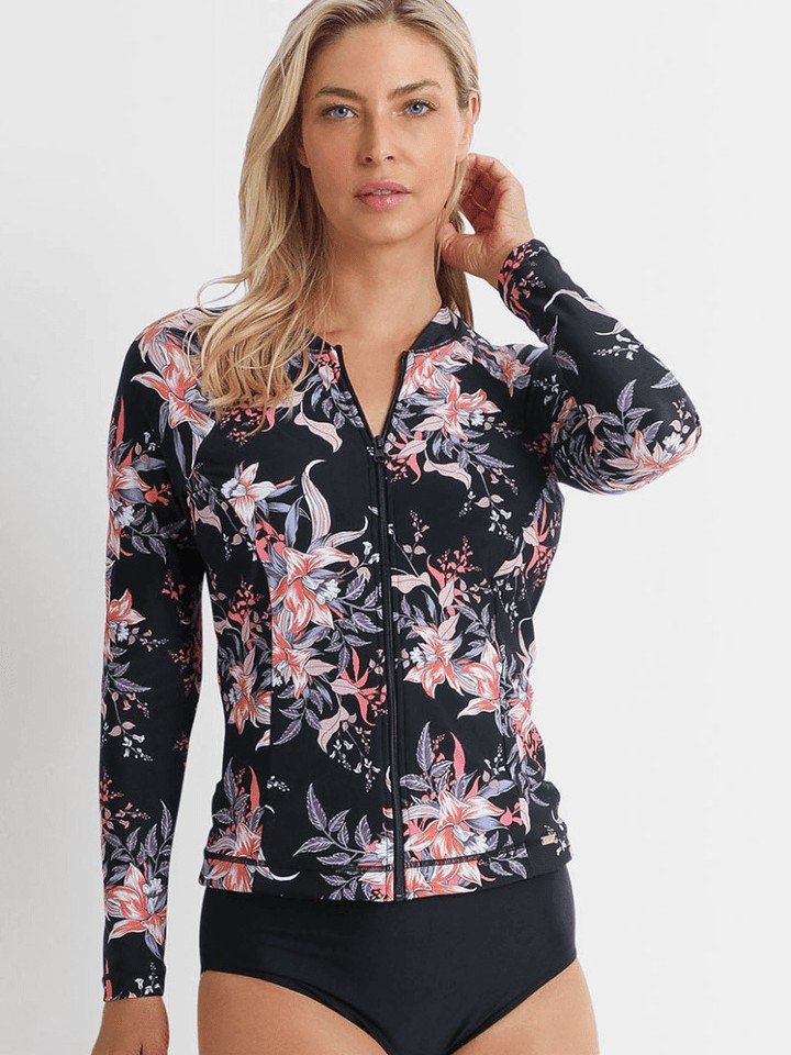 Woman wearing a long sleeve zip-front floral rash guard with a cropped hem and black bikini bottoms.