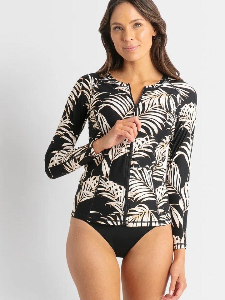 Black long sleeve zip front rash guard with white tropical leaf print and collarless neckline.