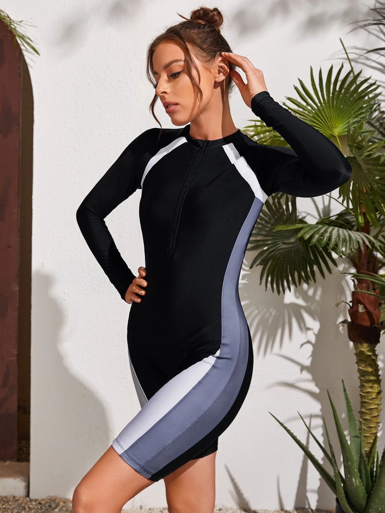 Model wearing a black long sleeve half-zip biker wetsuit with white and grey side panels.