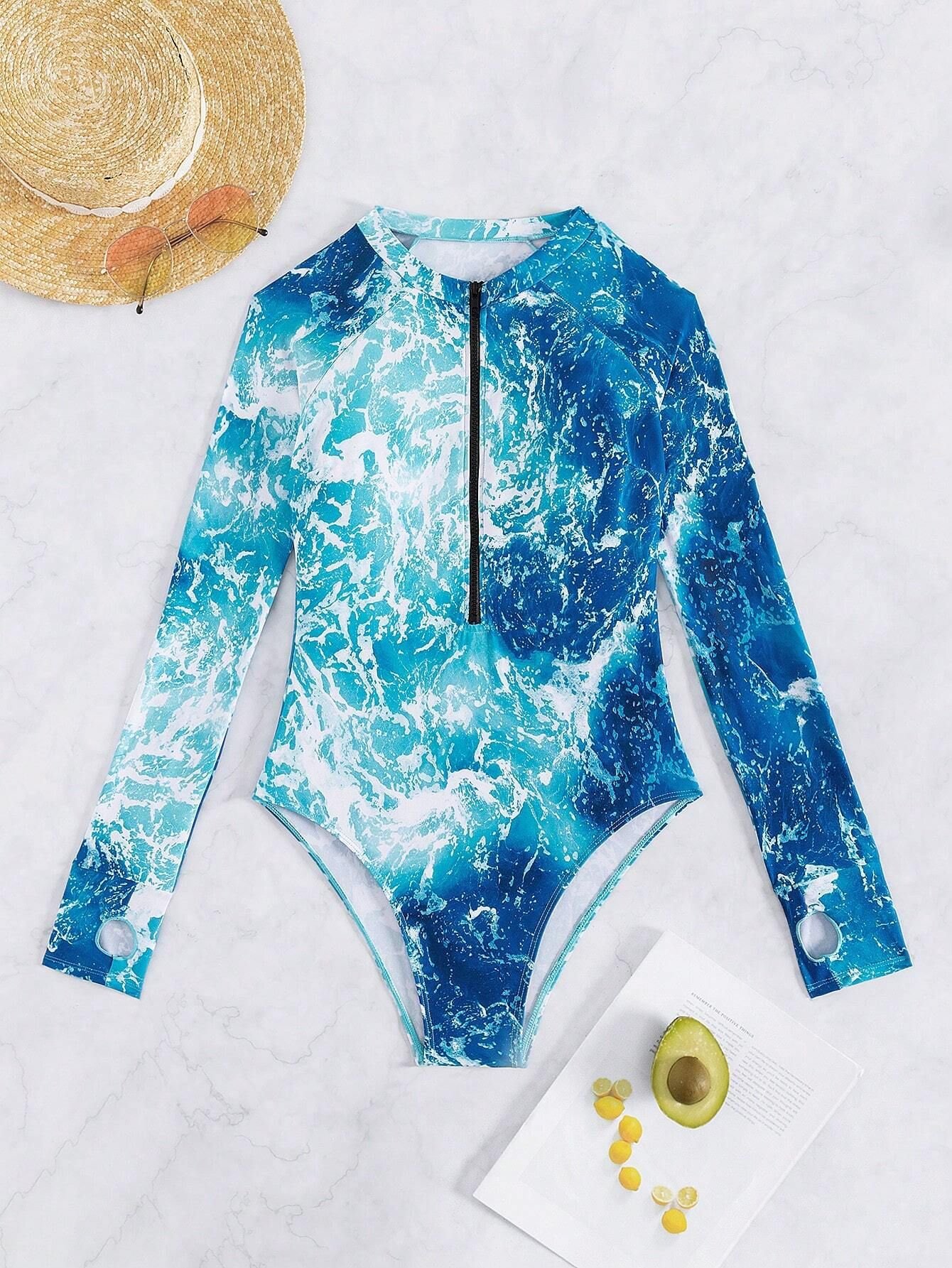 Blue and white ocean wave print long sleeve one-piece rash guard with front zip and thumbhole cuffs.