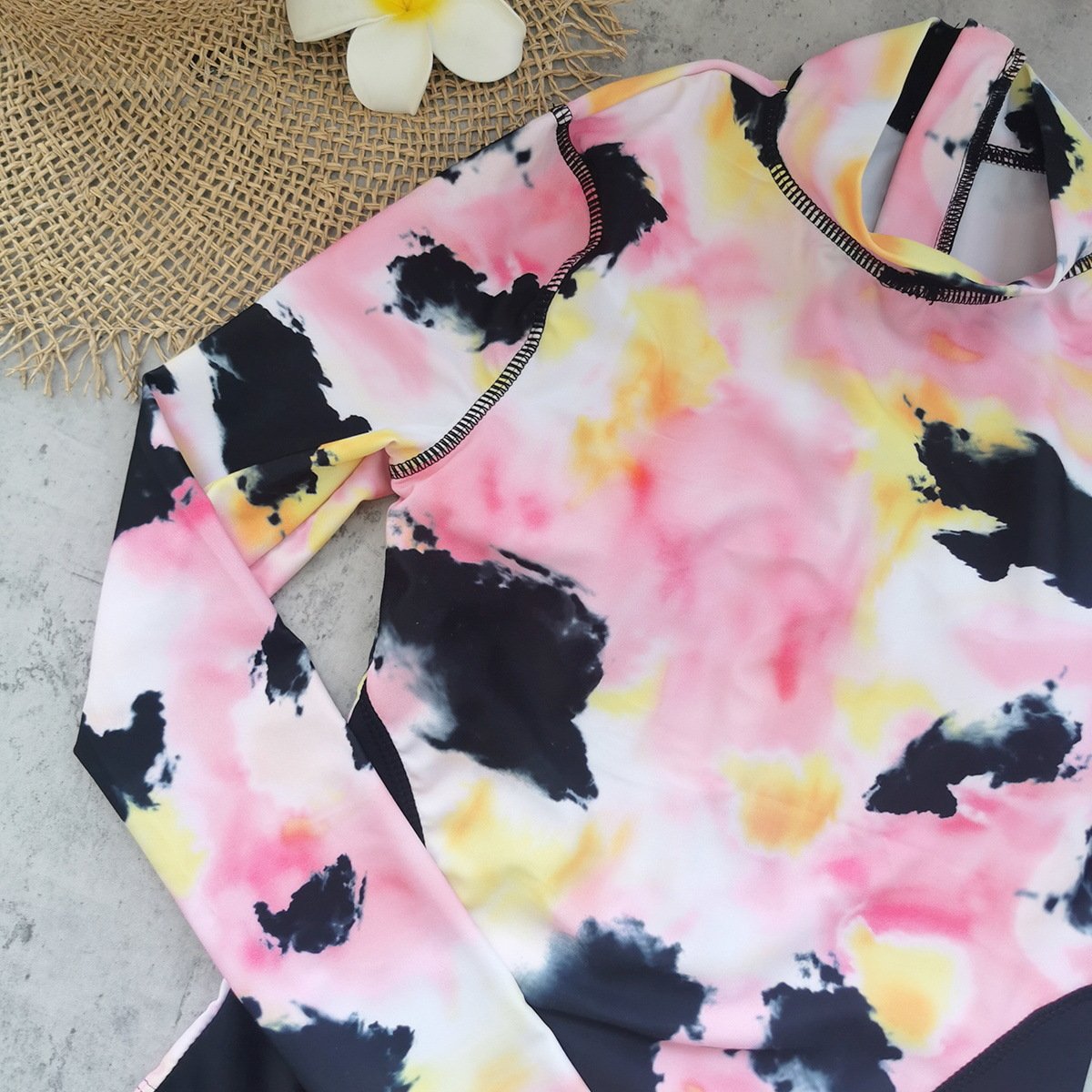 Pink, yellow, and black tie-dye long sleeve high neck rash guard with contrast stitching.