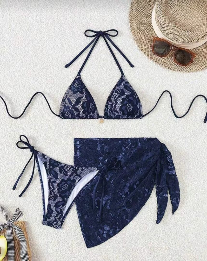 Navy blue floral lace three-piece bikini set with tie-side halter top, briefs, and wrap skirt.