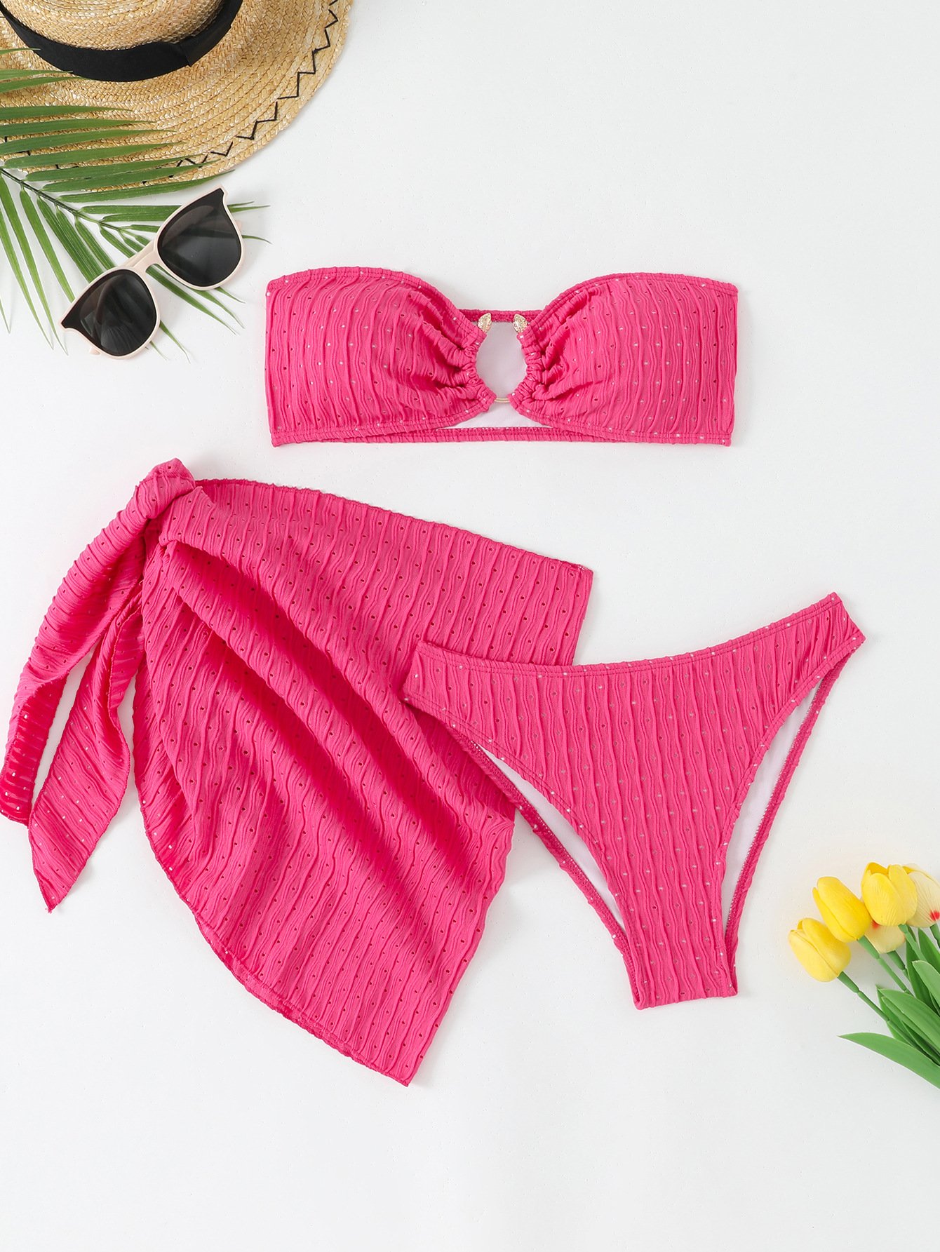 Pink three-piece swim set featuring a ruched bandeau top, bikini bottoms, and a wrap skirt cover-up.