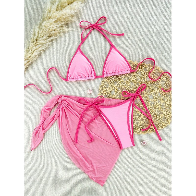 Pink three-piece bikini set with triangle halter top, tie-side bottoms, and wrap skirt cover-up.