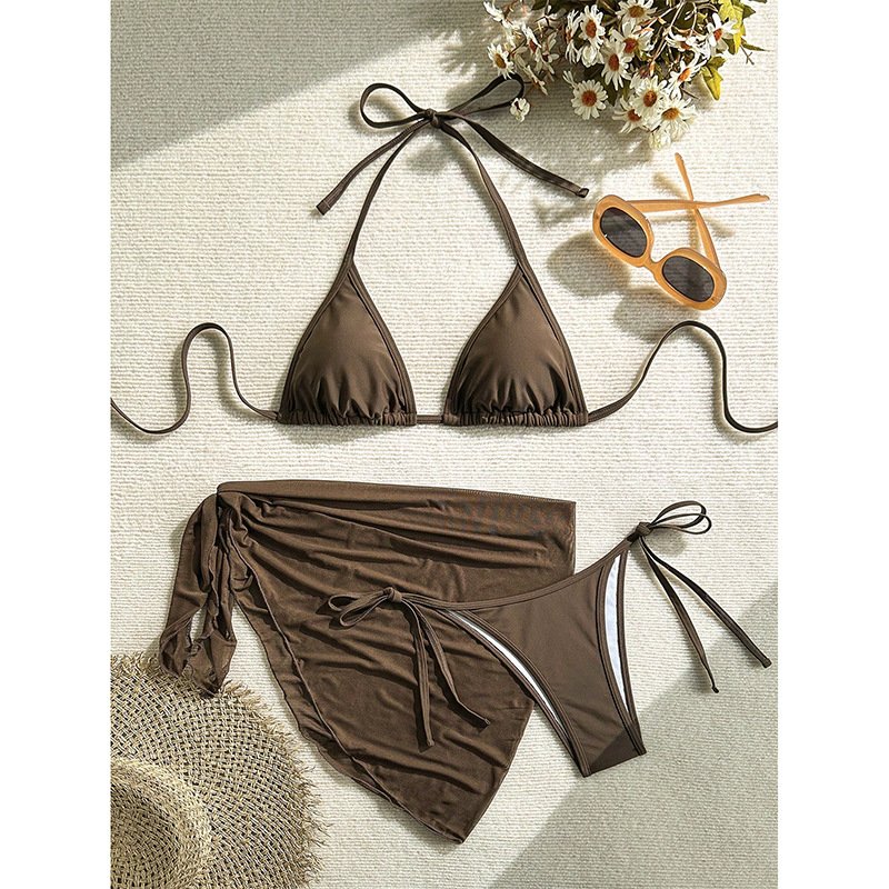 Brown three-piece bikini set featuring a triangle halter top, tie-side bottoms, and a matching wrap skirt cover-up.