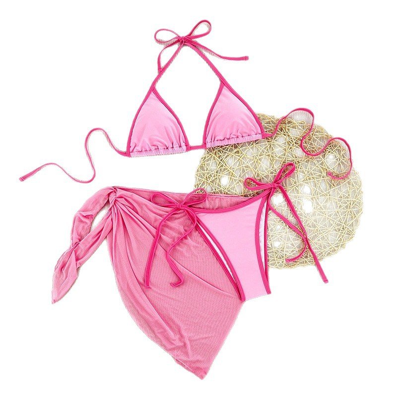 Pink three-piece bikini set featuring a triangle halter top, tie-side bottoms, and a matching wrap skirt cover-up.