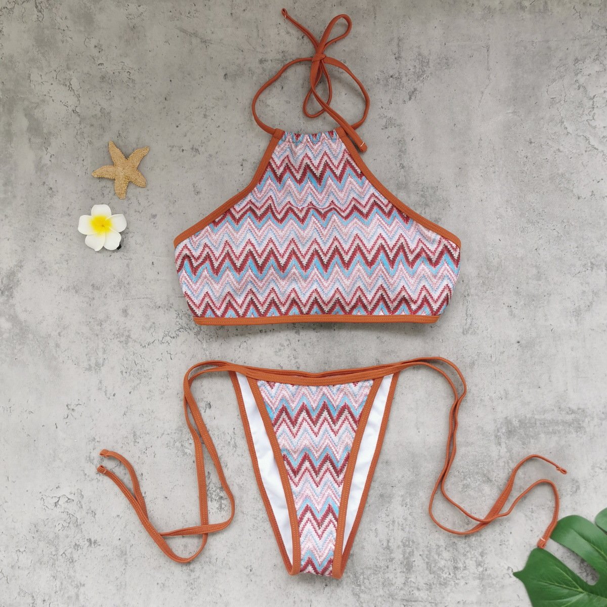 A three-piece zigzag print swimwear set with a halter top, tie-side bottoms, and a matching wrap skirt.