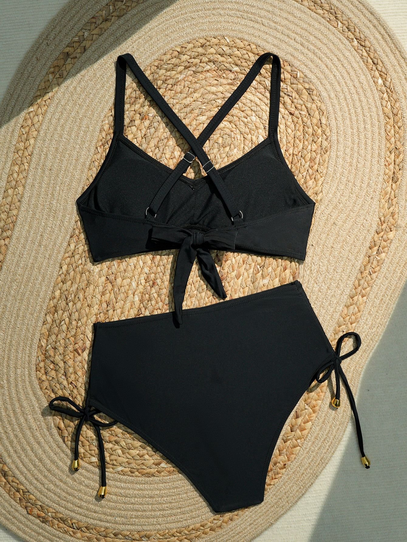Black two-piece bikini set featuring a halter crop top with crossback straps and a bow front, paired with