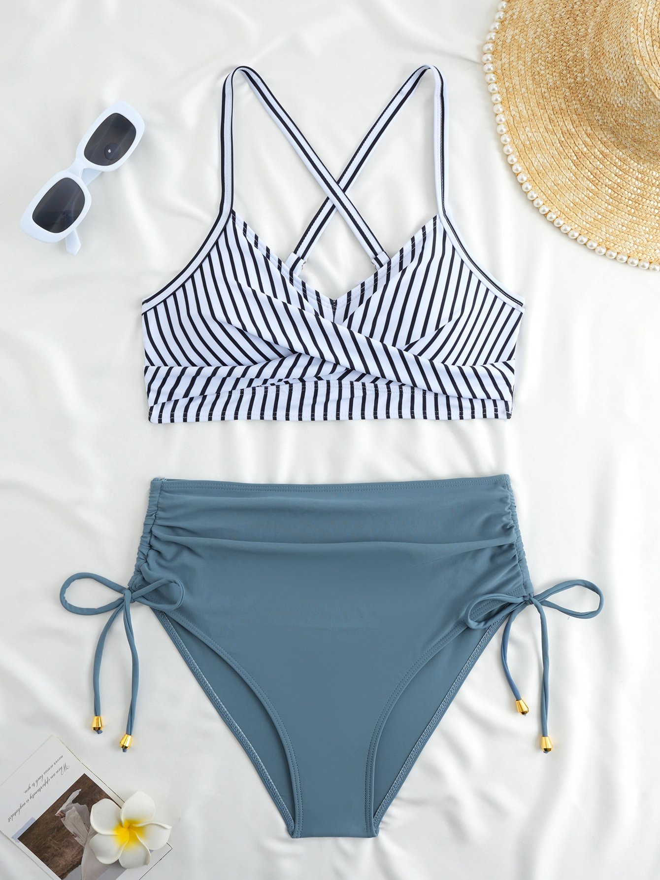 Striped halter crop top bikini with crossback straps and solid blue high-waist tie-side bottoms.
