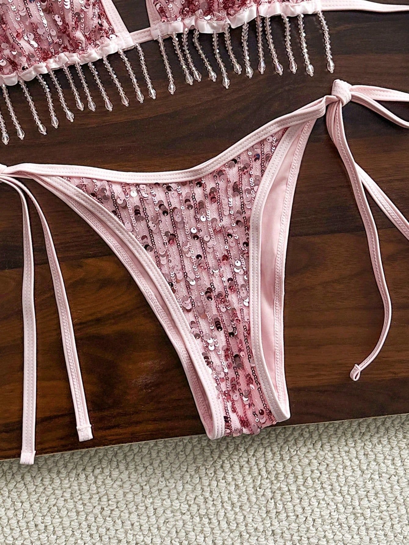 Pink sequin bikini bottoms with tie-side straps and fringe-trimmed top.