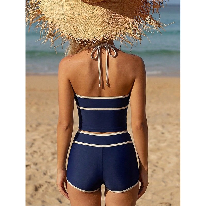 Back view of a navy blue two-piece swimsuit set with white contrast piping, featuring a halter tie top
