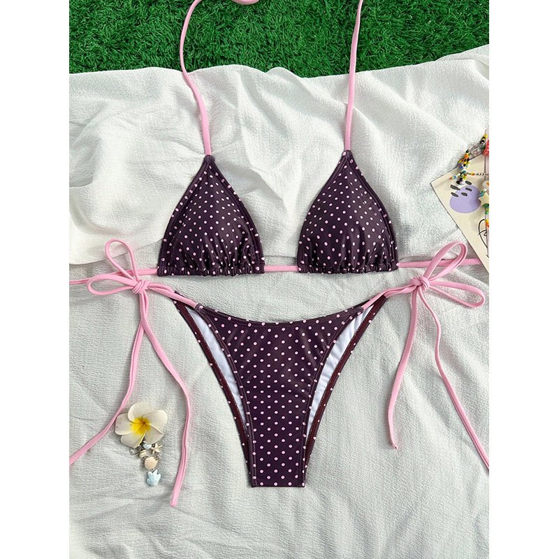 Purple polka dot tie-strap triangle bikini set with pink halter and side-tie straps on a white towel.
