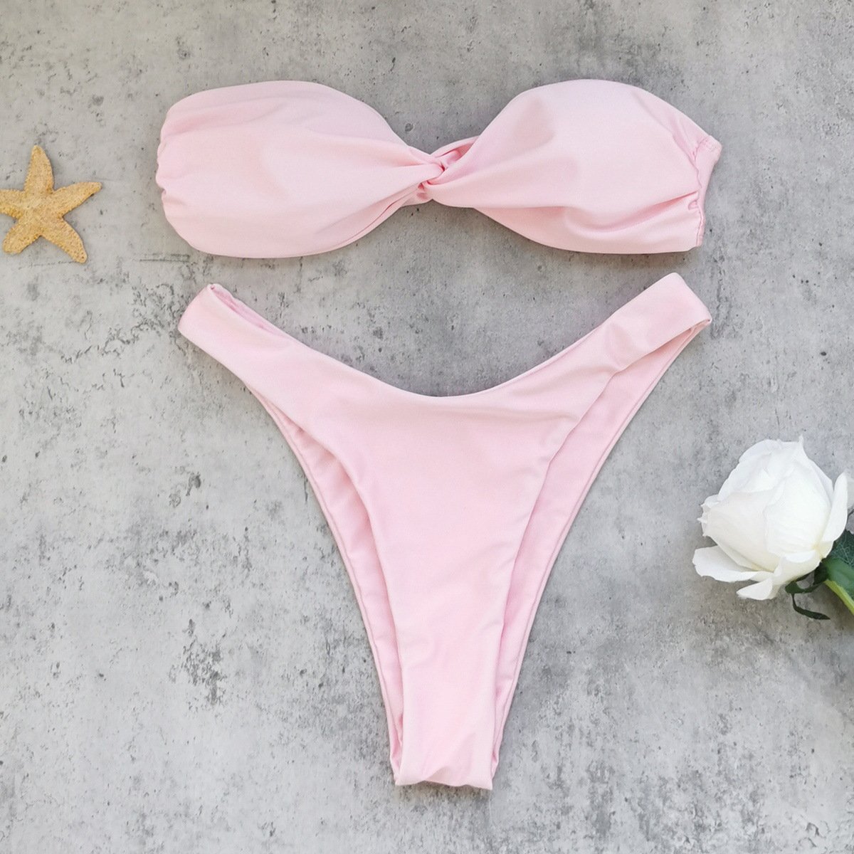 Pink strapless twist-front bandeau bikini set with high-cut thong bottoms.