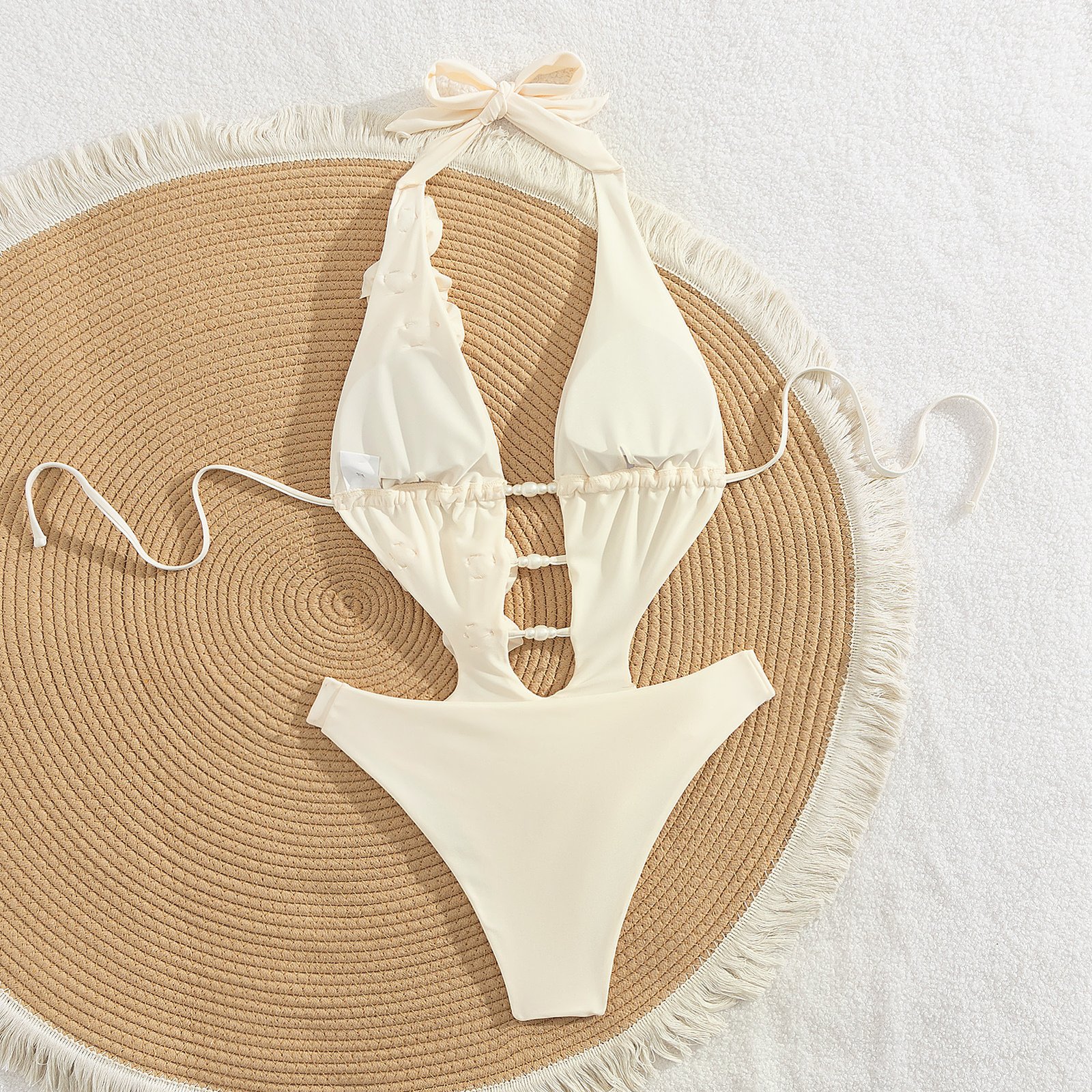 Cream white halter bikini set featuring pearl-link cutouts, floral appliques, and high-cut briefs.