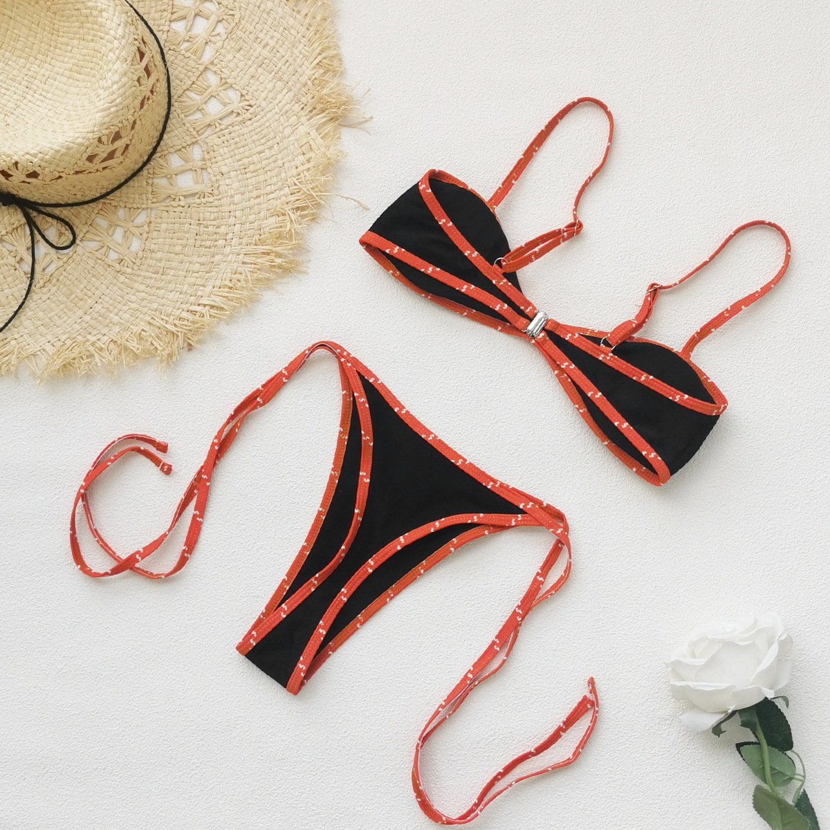 Black two-piece bikini set with orange piped trim, featuring an underwire halter top and side-tie bottoms.