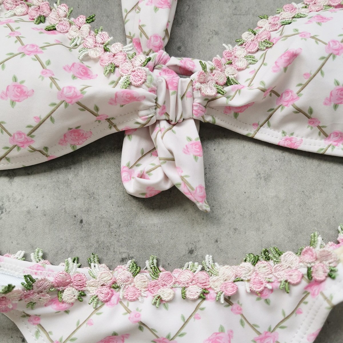 Close-up of a floral print bikini set featuring an underwire top with a front knot and embroidered floral