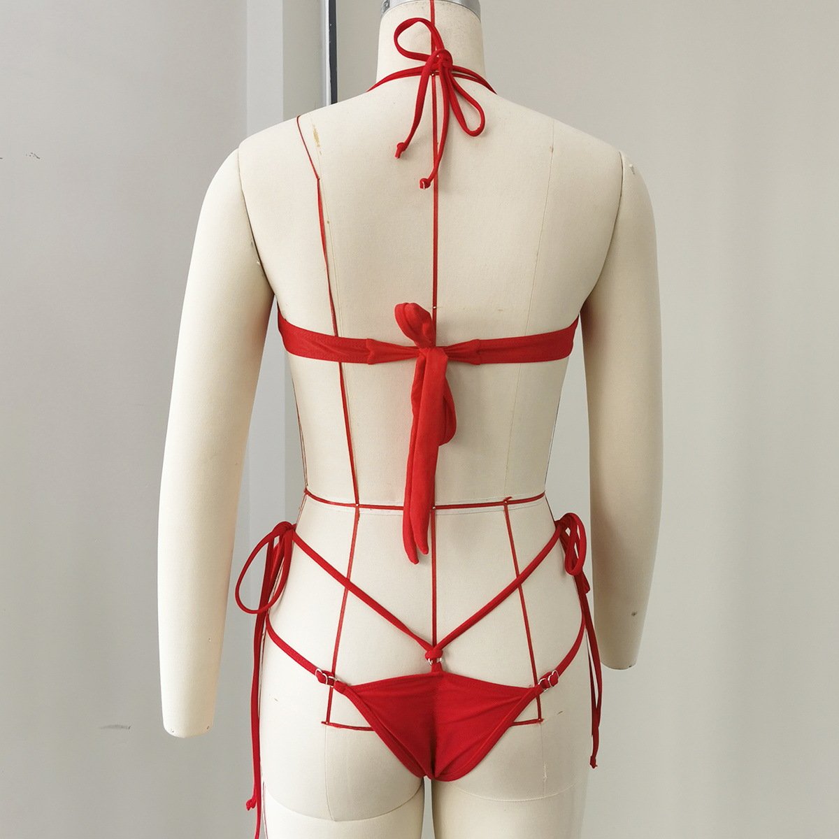 Back view of a red bikini set featuring a tie-back top and strappy thong bottoms on a mannequin.