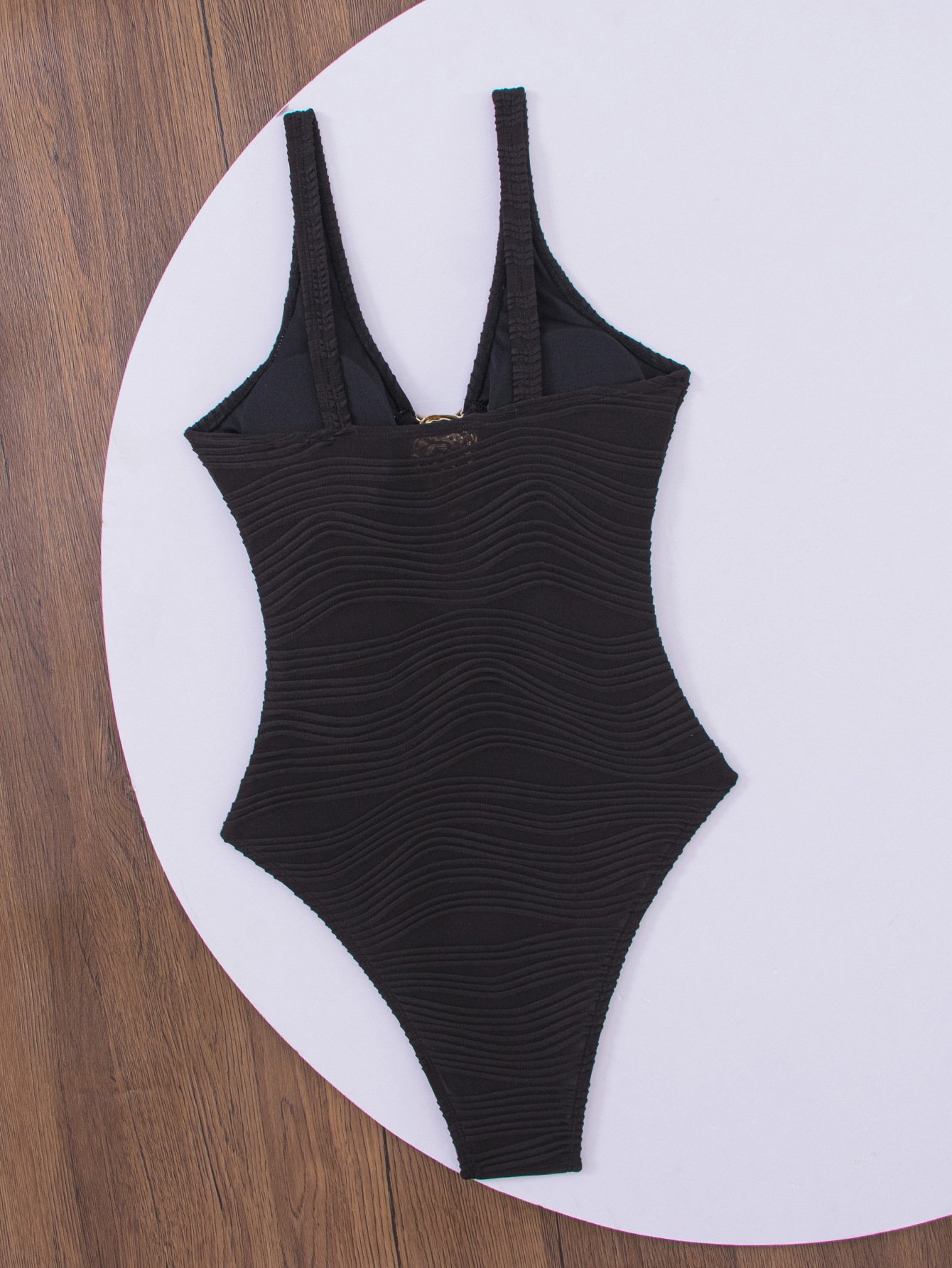 Black textured one-piece swimsuit with a deep V-neckline, thin straps, and a front keyhole detail.