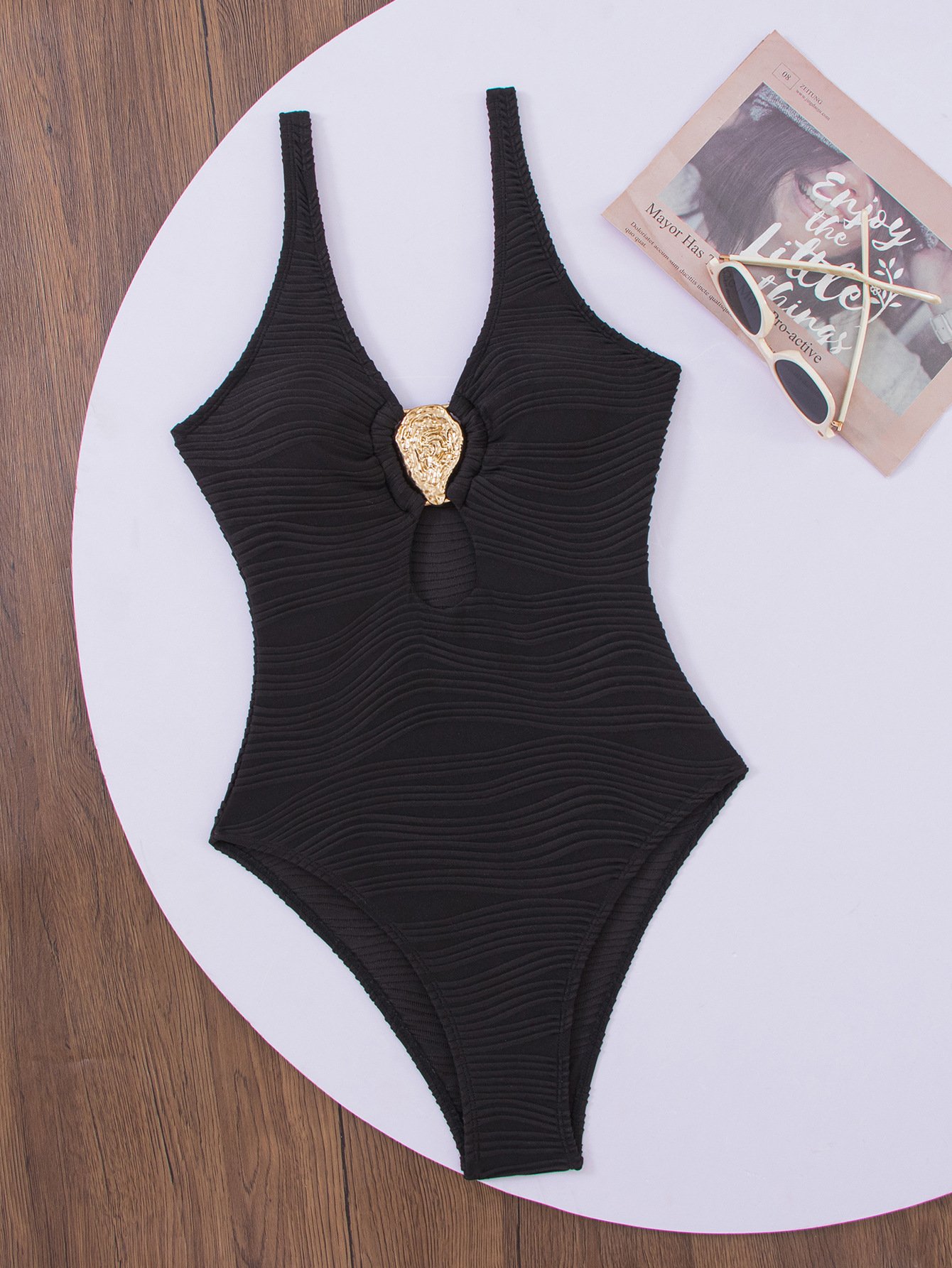 Black textured one-piece swimsuit featuring a deep V-neck, center front keyhole cutout, and gold decorative accent.
